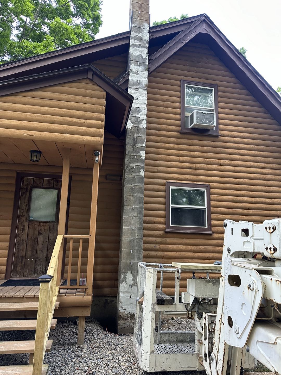 Before: bare block chimney with a lift in place beside the cabin