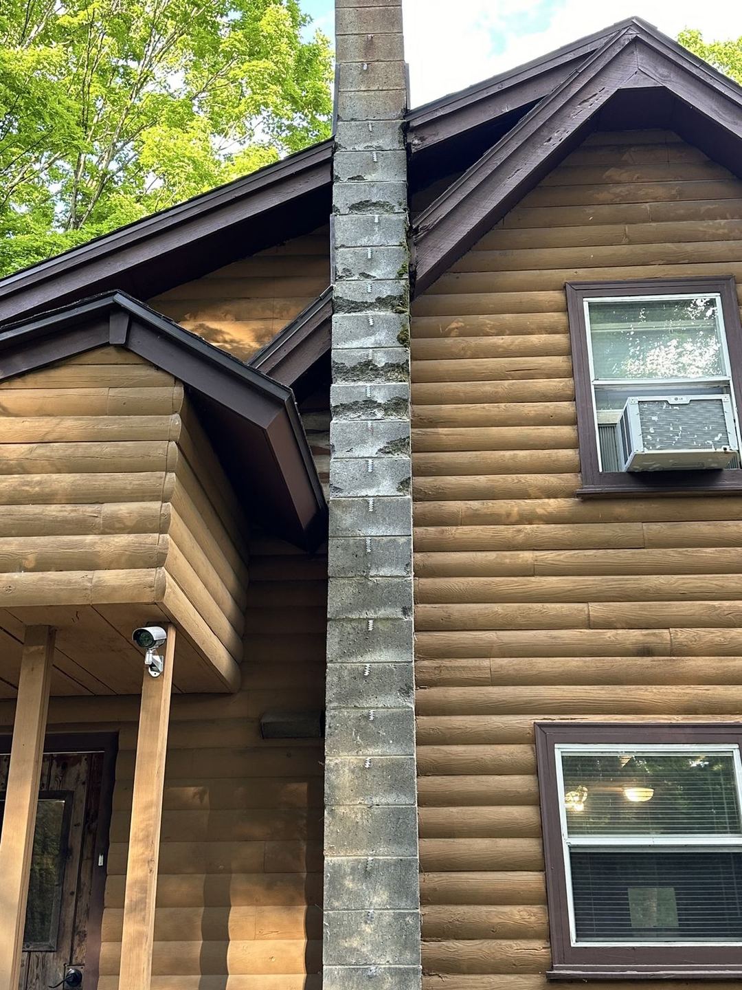 Before: bare weather-stained concrete block chimney on a log cabin