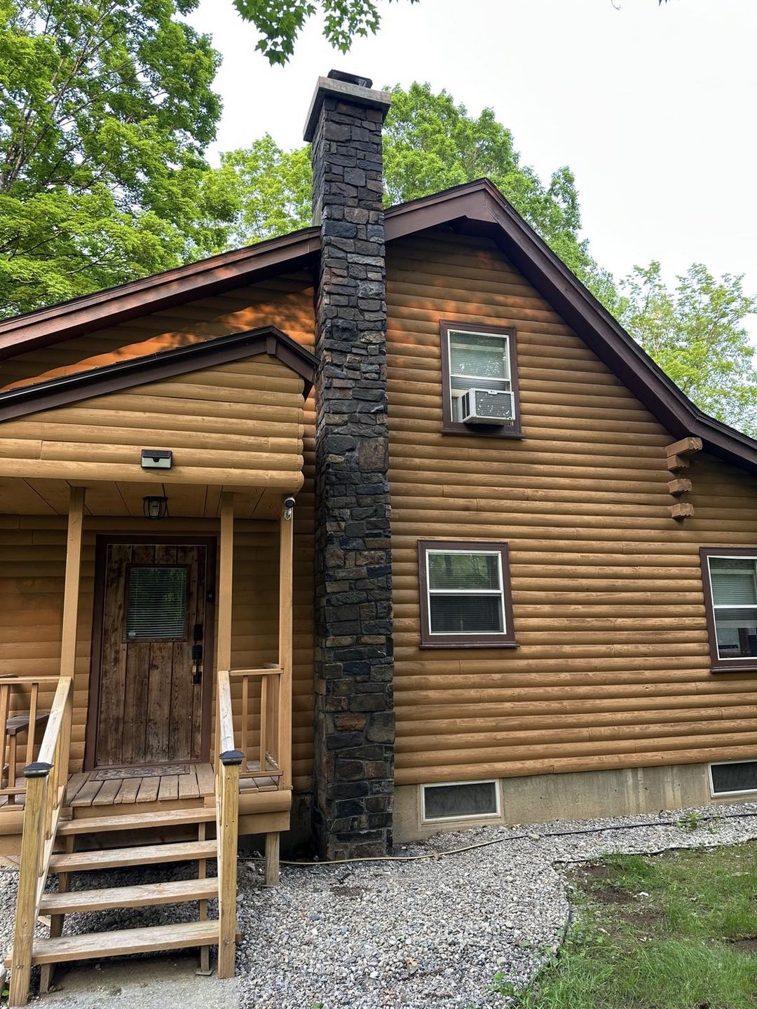 Finished full-height stone chimney veneer on a log cabin, built by Dennett Stone & Property Co.