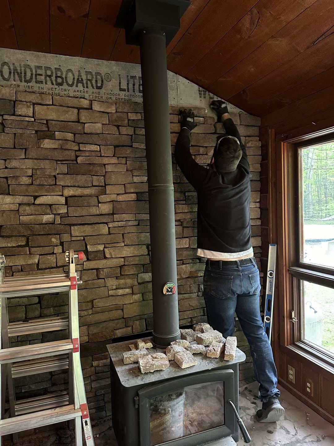 Installing stone veneer on the wood-stove wall by hand