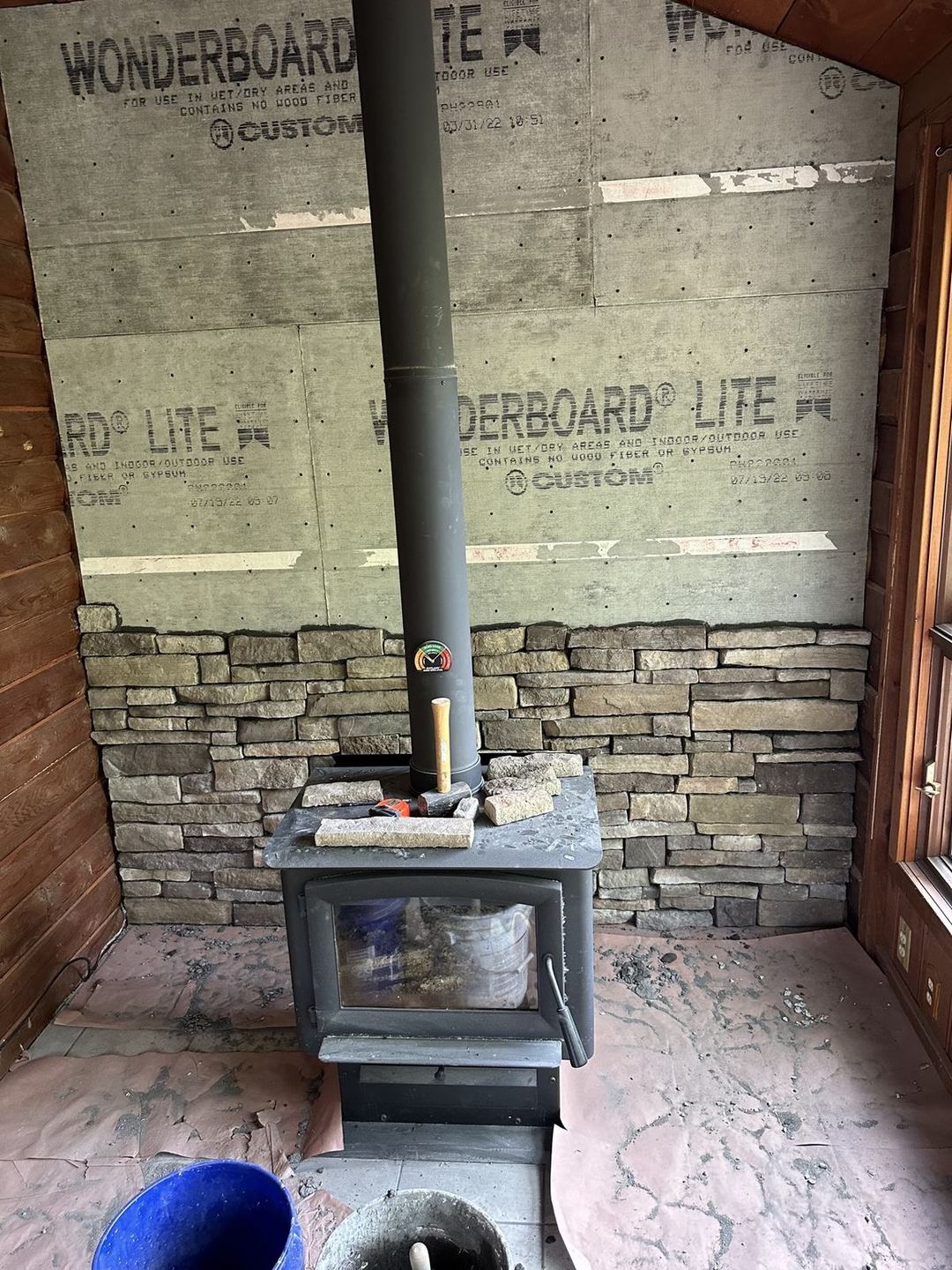 Wood-stove wall with cement backing board and the first courses of stone