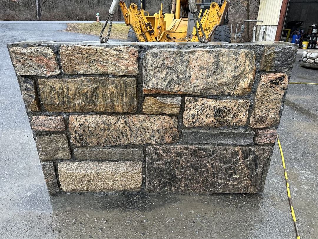 Granite block wall section being moved by a front loader